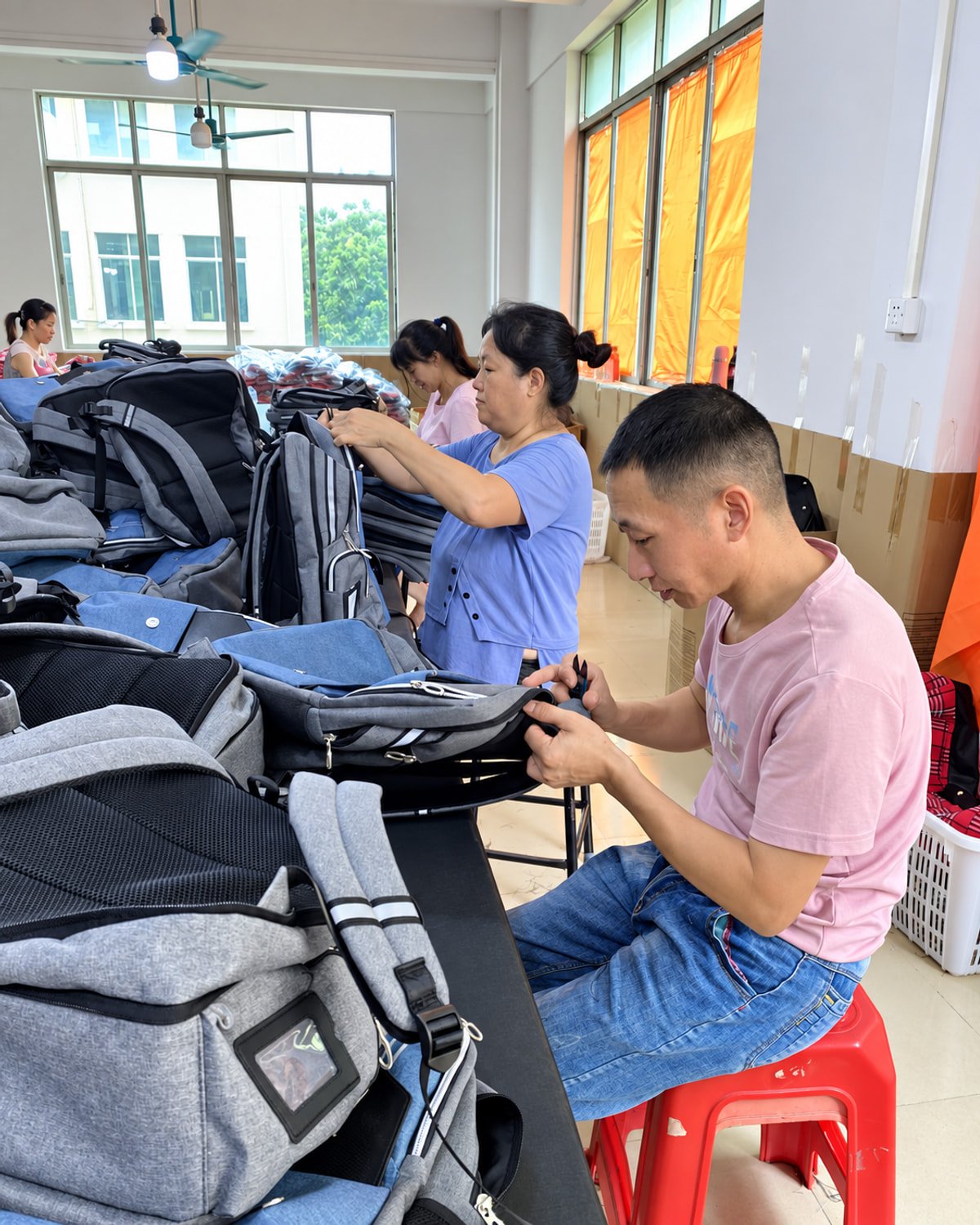 Workers assembling and inspecting finished backpacks