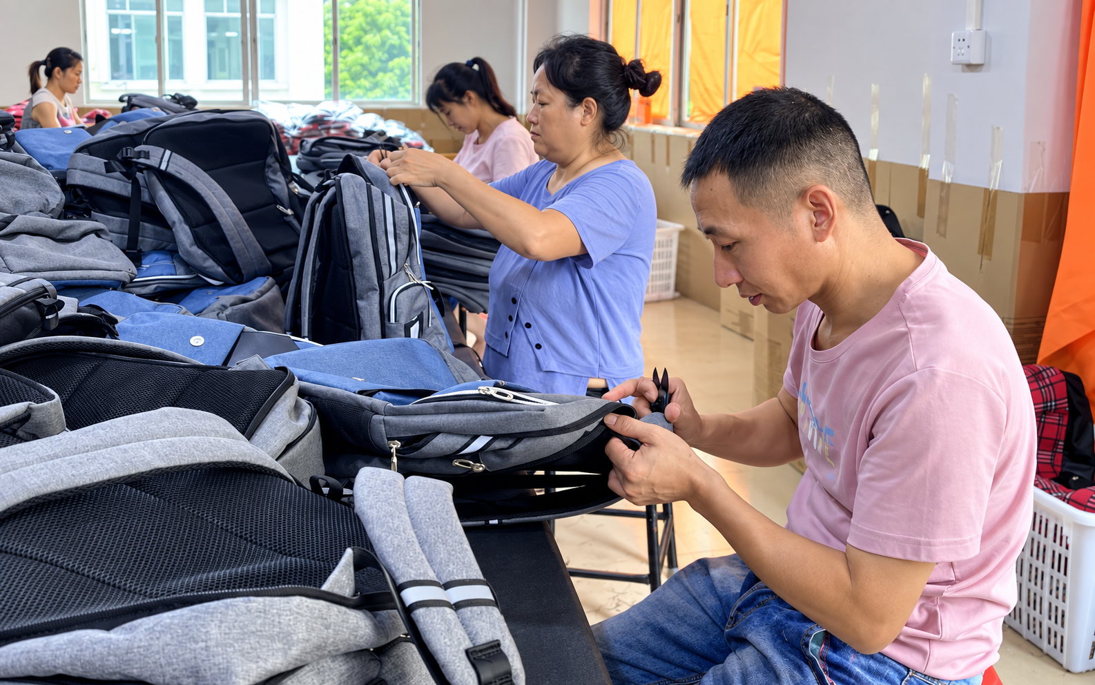 Workers assembling and finishing backpacks at Pengnan Bags