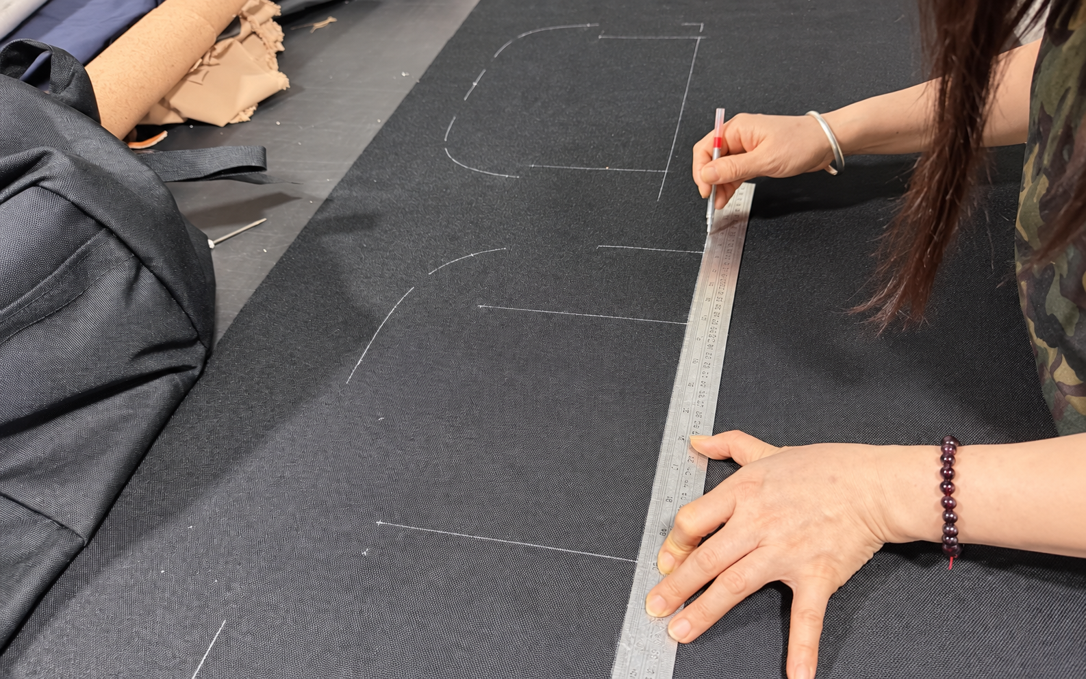Worker marking bag fabric panels before cutting at Pengnan Bags