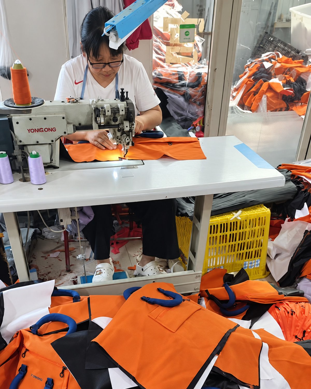Worker sewing orange custom bags during production